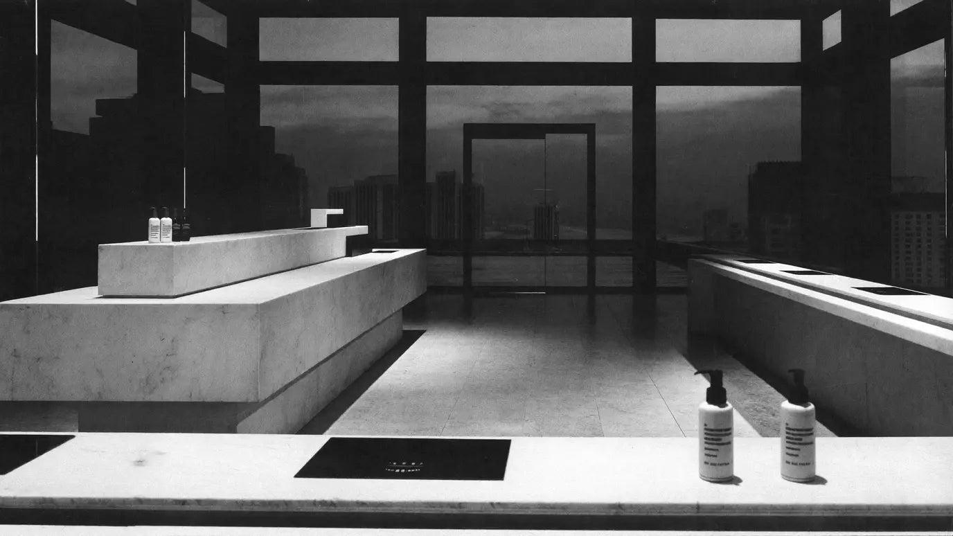 A quiet modern retail interior at dusk, a few bottles spaced along a long counter