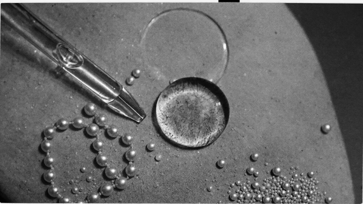 A drop of serum on stone beside caviar pearls and a glass pipette