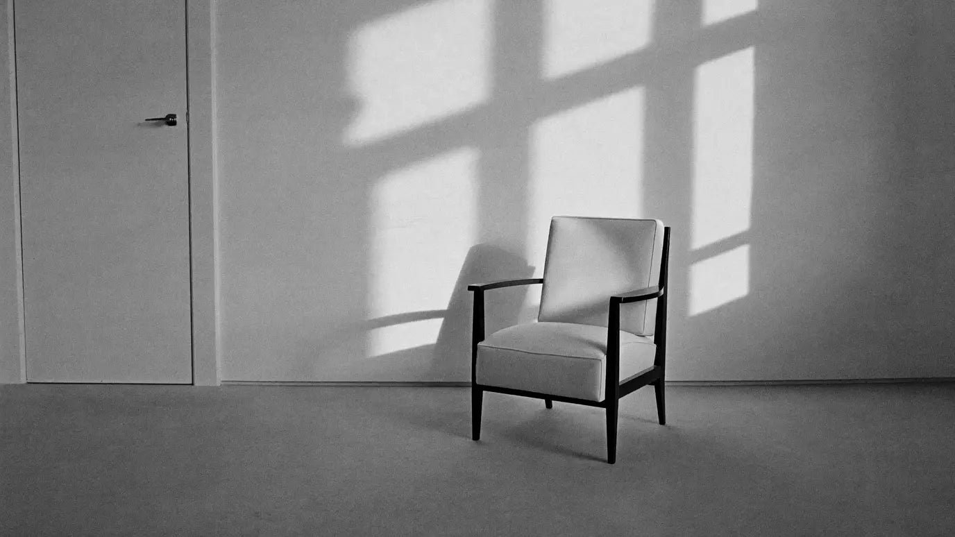 A quiet interior with a single chair and morning light across a plaster wall